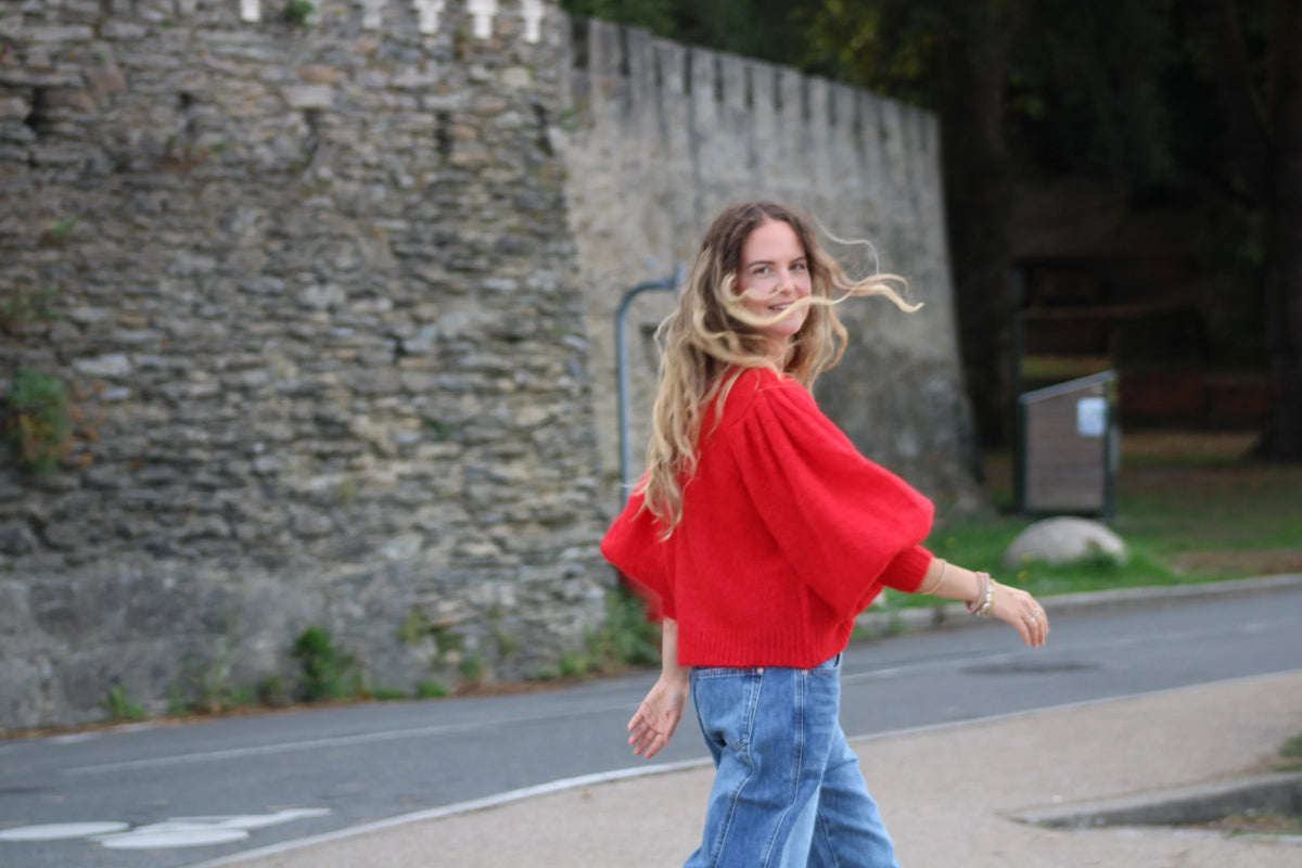 Silhouette en pull rouge devant un mur de pierre à Pornic — Nouveautés Les Demoiselles
